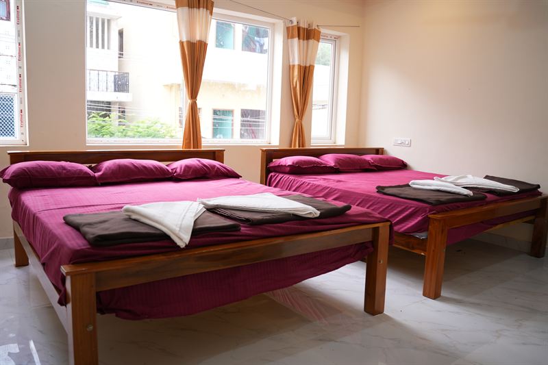 Large family room with two double beds and orange striped curtains in daylight