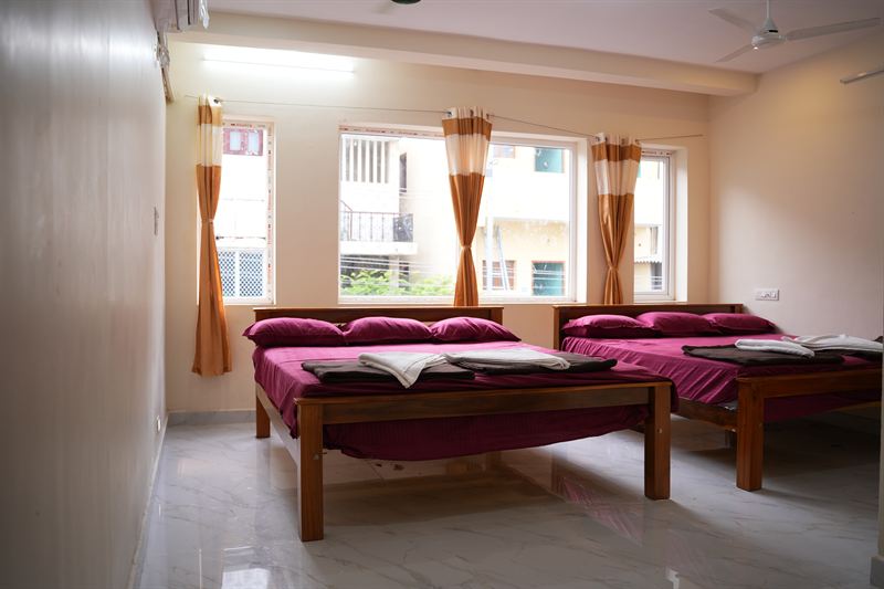 Family room with two beds and three orange-curtained windows
